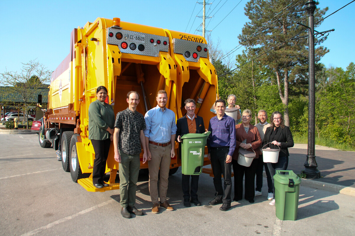 Owen Sound Council standing in front of a garbage truck with a green bin