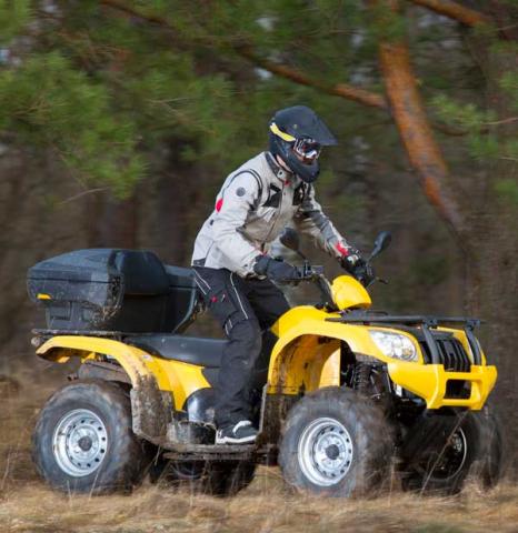 Person riding a yellow ATV down a trail.