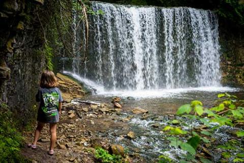 Child standing in front of a waterfall