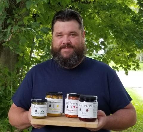 Eli McFadden holding jars of products from Funky Ferments