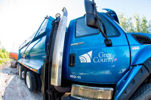 A Grey County truck backs towards a road construction project.