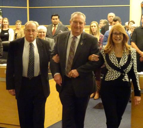 Alan Barfoot is lead to the Warden's chair by fellow County Councillors Gail Ardiel and Harley Greenfield