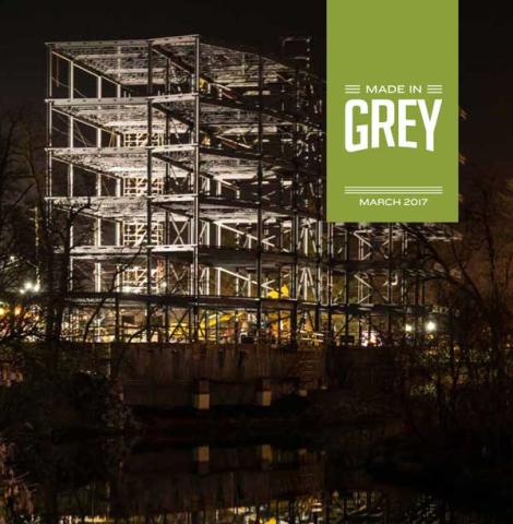 Cover of the Made in Grey magazine showing the beams of a new condominium lit up in the night sky above downtown owen sound.