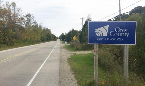 A grey county road sign on the shoulder of Grey Road 1