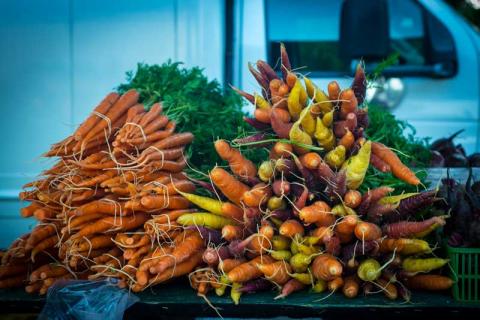 Bundles of fresh root vegetables are tied together and displayed on a table at a local farmers' market