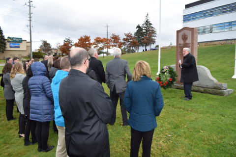 Councillors and staff gather on the lawn in front of the Administration Building as a wreath is laid at the war memorial.