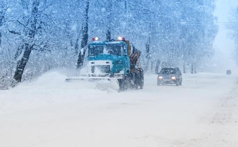 A snow plow pushes snow off the road