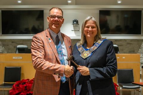 2025 Warden Andrea Matrosovs (right) receives the Chain of Office and gavel from outgoing Warden, Brian Milne. 