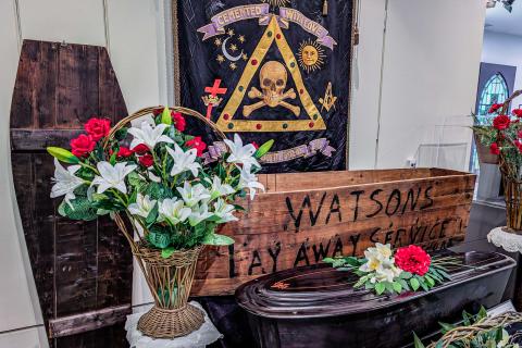 A funeral floral arrangement and tapestry featured in Going Out in Style.